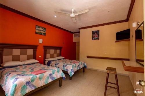 2 Betten in einem Zimmer mit orangefarbenen Wänden in der Unterkunft Hotel los Arcos in Izamal