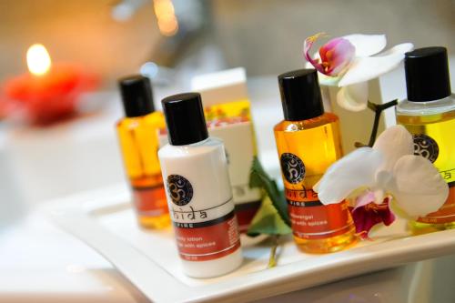 a group of four bottles of moisturizers and flowers on a shelf at Boutique Hotel Diana in Madonna di Campiglio