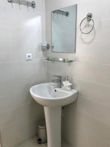 a white bathroom with a sink and a mirror at Hotel CHARLI in Gonio