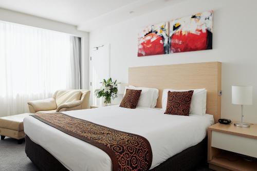 a hotel room with a large bed and a chair at The Ville Resort - Casino in Townsville