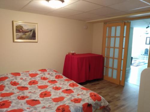 um quarto com uma cama e uma mesa com uma toalha de mesa vermelha em Manoir la Licorne em Notre-Dame-du-Lac