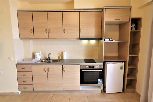 a kitchen with wooden cabinets and a white refrigerator at Dolphins Apartments in Loutra Edipsou