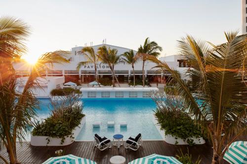 a hotel with a swimming pool with chairs and palm trees at The Ville Resort - Casino in Townsville