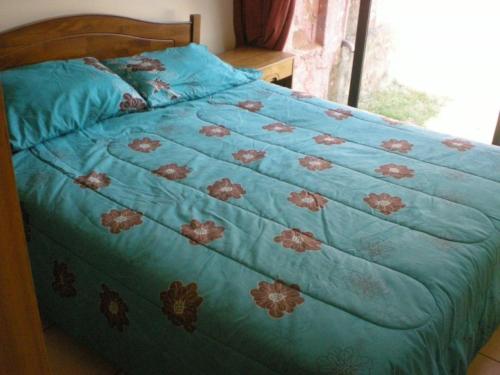 a bed with a blue blanket with flowers on it at La Gran Casona de Olmue in Olmué