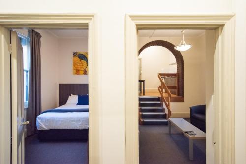 a bedroom with a bed and a stairway leading into a room at The Mile End Hotel in Adelaide