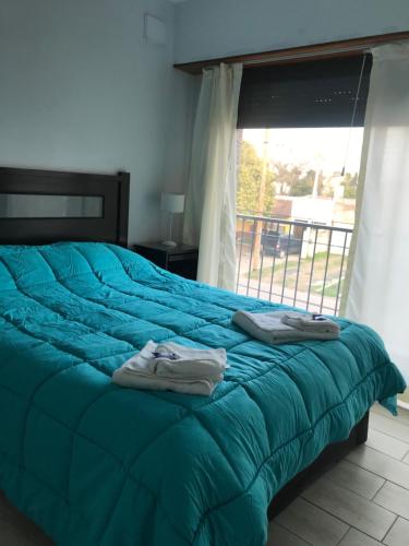 1 dormitorio con cama con sábanas azules y ventana en Departamento en Chascomús a dos cuadras de laguna en Chascomús