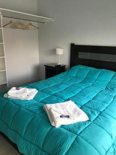 Un dormitorio con una cama azul con toallas. en Departamento en Chascomús a dos cuadras de laguna en Chascomús