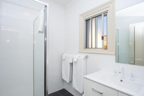 a white bathroom with a shower and a sink at The Mile End Hotel in Adelaide
