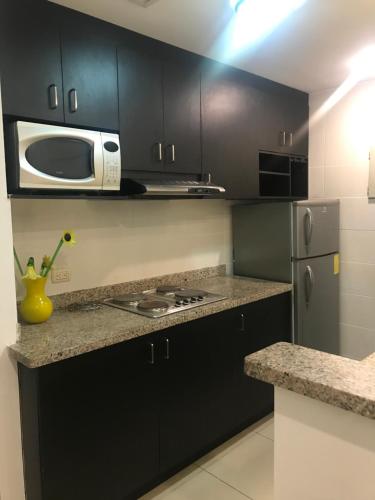 una cucina con mobili neri e un microonde di Suite amoblada súper cómoda a Guayaquil
