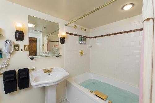 a bathroom with a sink and a bath tub at Lake Pointe Inn in McHenry