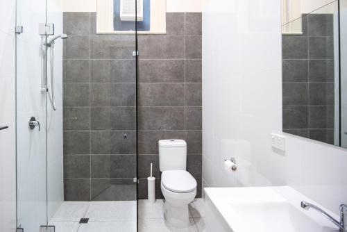 a bathroom with a shower and a toilet and a sink at The Mile End Hotel in Adelaide