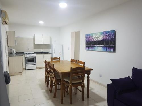 cocina y comedor con mesa de madera y sillas en Apart Ocampo Catamarca en San Fernando del Valle de Catamarca