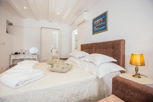 Schlafzimmer mit einem Bett mit weißer Bettwäsche und Kissen in der Unterkunft Boutique Room Kaliopi in Hvar