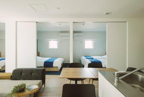 a room with two beds and a kitchen with a sink at Seacruise House Navio in Kami Amakusa