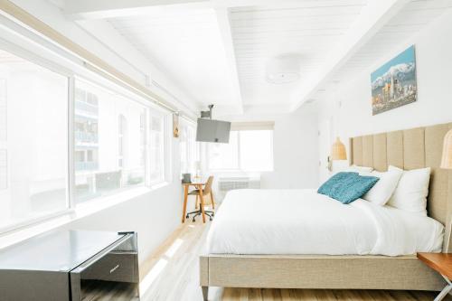 a white bedroom with a bed and a glass table at The Belmont Shore Inn in Long Beach