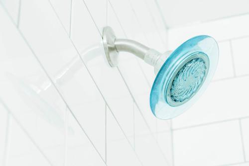 a shower head hanging on a white tiled wall at The Belmont Shore Inn in Long Beach