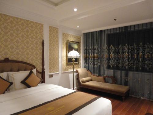 a bedroom with a bed and a chair and a lamp at Hoang Nham Luxury Hotel in Ta Lan Than