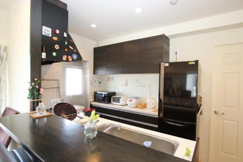 een keuken met een zwarte koelkast en een wastafel bij Alaha Blue Resort 6F -SEVEN Hotels and Resorts- in Chatan