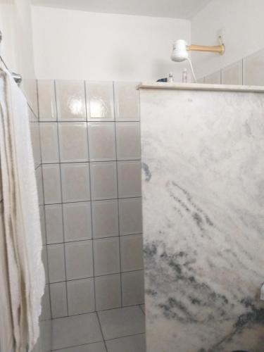 uma casa de banho com um chuveiro e uma bancada em mármore. em HOSTEL Bom Gosto em Canavieiras