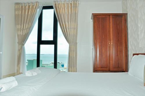 ein Schlafzimmer mit einem Bett und einem großen Fenster in der Unterkunft Khách sạn Trâm Anh in Quy Nhon