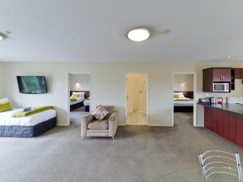 a hotel room with a bed and a chair and a kitchen at ASURE Avenue Motor Lodge in Timaru