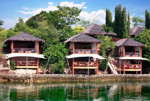 a group of huts next to a body of water at Badian Island Wellness Resort in Badian