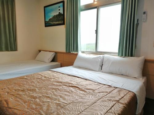馬公市的住宿－情定海豚灣民宿，酒店客房设有两张床和窗户。