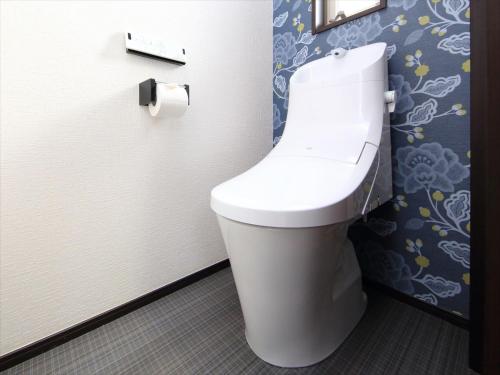 a white toilet in a bathroom with a roll of toilet paper at COTO Tokyo Nakano in Tokyo