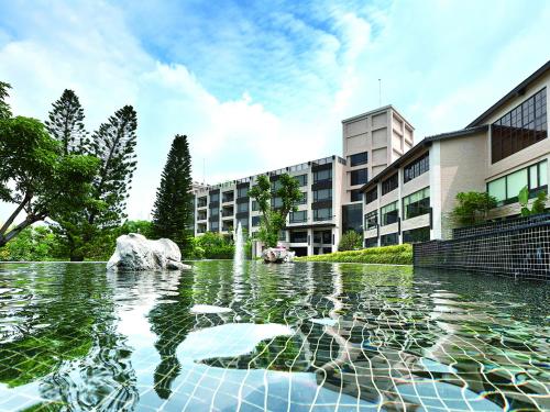 a pool of water with a fountain in front of a building at Spring Hill Resort in Tianliao