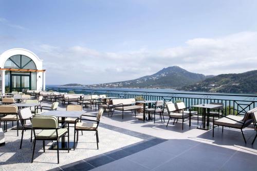 a restaurant with tables and chairs and a view of the water at Dolce by Wyndham Athens Attica Riviera in Vravrona