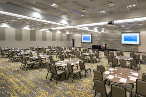 a conference room with tables and chairs and a screen at The Summit Hotel in Cincinnati