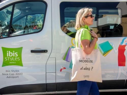 a woman holding a sign in front of a truck at ibis Styles Nice Cap 3000 in Saint-Laurent-du-Var