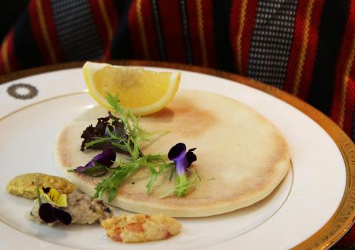 a plate of food with a tortilla and a lemon at The Trans Luxury Hotel Bandung in Bandung