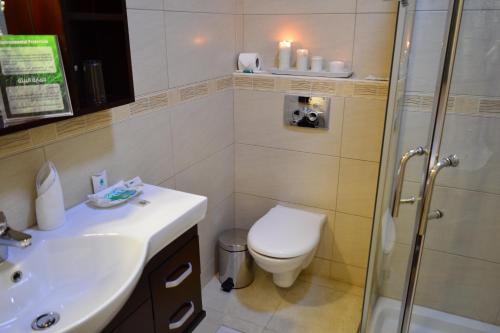 a bathroom with a toilet and a sink and a shower at Comfort Hotel Suites in Amman