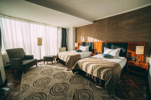 a hotel room with two beds and a chair at Damas International Hotel in Bishkek