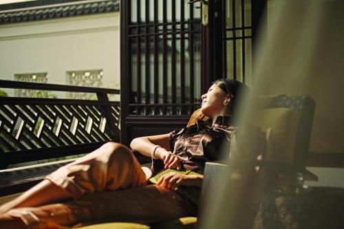 a woman sitting on a balcony looking out a window at Four Seasons Hotel Hangzhou at West Lake in Hangzhou