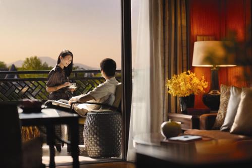 a man and woman sitting on a balcony in a hotel room at Four Seasons Hotel Hangzhou at West Lake in Hangzhou