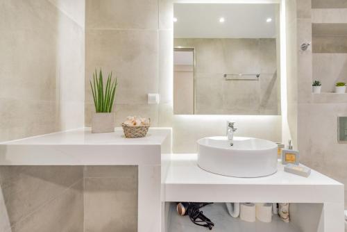 a white bathroom with a sink and a mirror at Stylish & Bright Apartment in the City Centre in Zakynthos Town