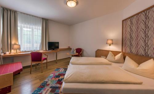 a hotel room with two beds and a desk at Hotel Linde Durbach in Durbach