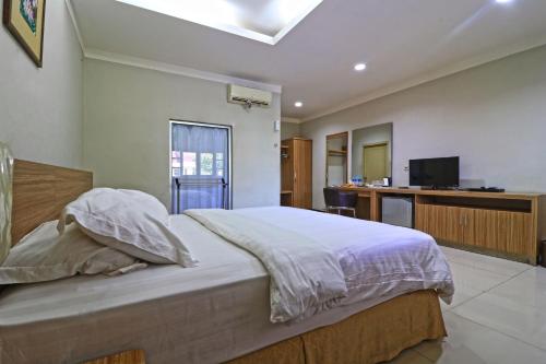 a bedroom with a bed and a desk and a television at Hotel Sampaga in Banjarmasin