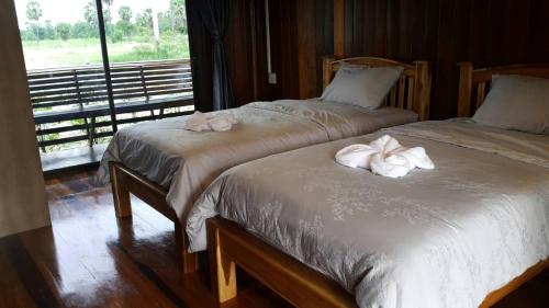 - 2 lits installés côte à côte dans une chambre avec fenêtre dans l'établissement ธนาวดี บูติคแอนด์ รีสอร์ท, à Phetchaburi