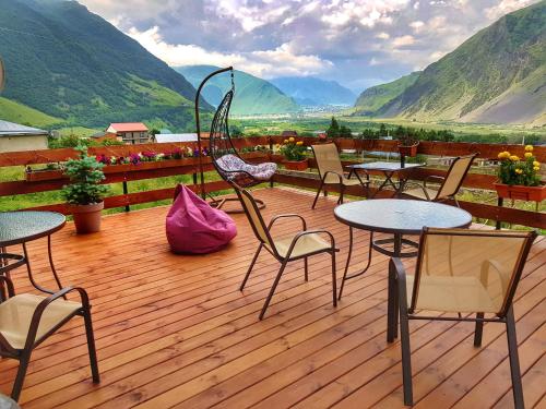 a patio with tables and chairs on a wooden deck at Sunshine Kazbegi in Stepantsminda