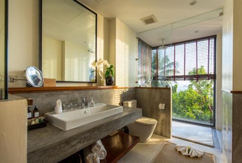 a bathroom with a sink and a toilet and a mirror at L2 Residence in Laem Set Beach