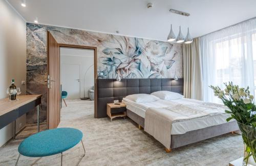 - une chambre avec un grand lit et une peinture murale dans l'établissement Hotel Zorza, à Kołobrzeg