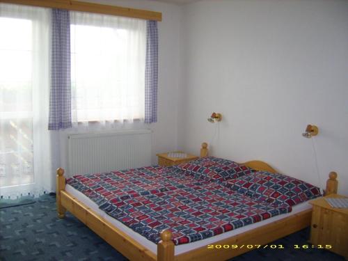 a bedroom with a bed with a quilt on it at Pension Holubec in Benecko