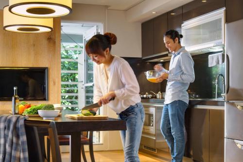 a woman and a man are preparing food in a kitchen at Gloria Residence in Taipei