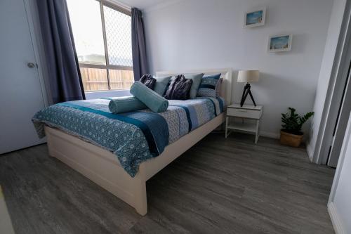 a bedroom with a bed with blue pillows and a window at Sanctuary Beach Retreat in Gold Coast