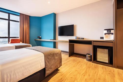 a hotel room with a bed and a desk with a tv at TROVE Johor Bahru in Johor Bahru