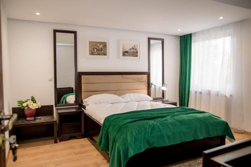 a bedroom with a large bed with a green blanket at Hotel THR Center in Curtea de Argeş