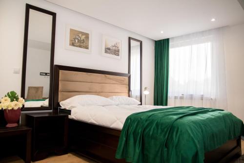 a bedroom with a bed with a green blanket on it at Hotel THR Center in Curtea de Argeş